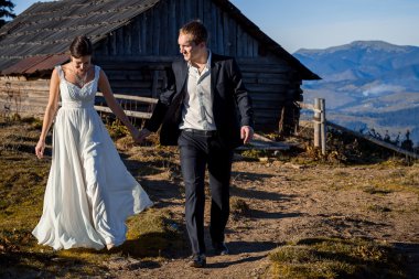 Wedding couple holding hands on the countryard. Honeymoon in  Carpathian mountains