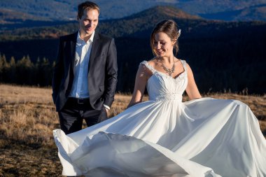 Gorgeous wedding couple posing on the mountain peak. Sunny day