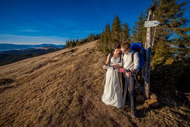 Wedding tourist couple with map coming up to the mountain