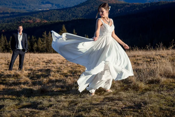 Hermosa novia baila ante su novio en el campo. Luna de miel en las montañas — Foto de Stock