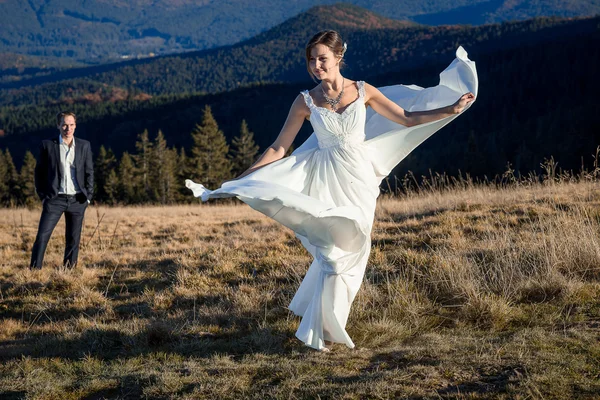 Красива наречена танцює перед своїм нареченим на полі. Медовий місяць у горах — стокове фото