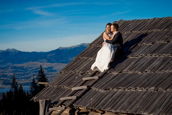 Bruidspaar zittend op het dak van het landhuis. Huwelijksreis in Bergen — Stockfoto