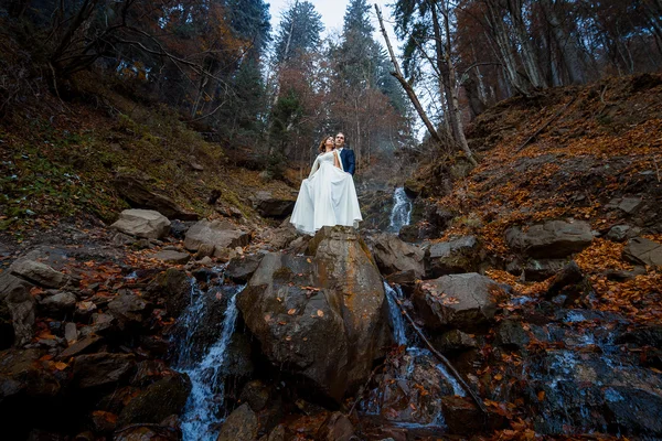Pareja de boda se abraza suavemente en la cascada. Día brumoso en las montañas — Foto de Stock