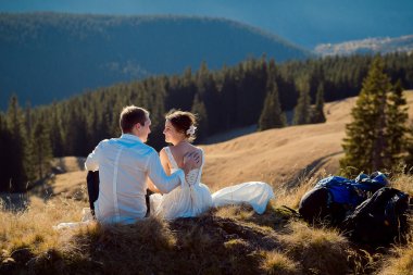 Happy wedding couple sitting on the mountain peak. Sunny day in Alps