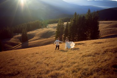 Mutlu düğün çift çalıştıran ve sahip eğlenceli dağlarla çevrili alan üzerinde
