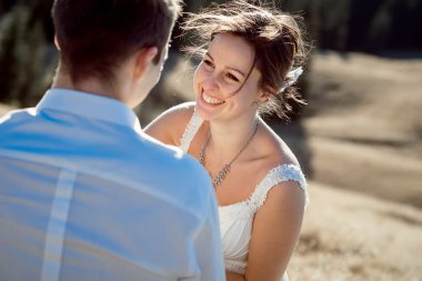 Happy freckled bride smiles to her groom. Sunny field on background