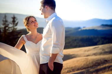 Gelin ve damat sevgiyle bakıyoruz. Dağlar arka plan