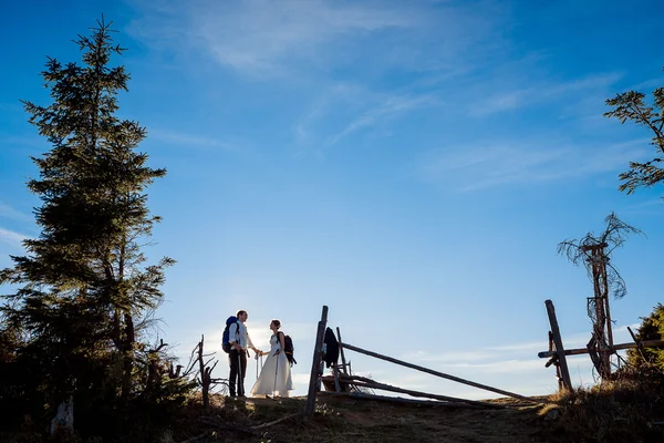 Happy newlyweds walking with mountain equipment on the Alpine countryside — стокове фото