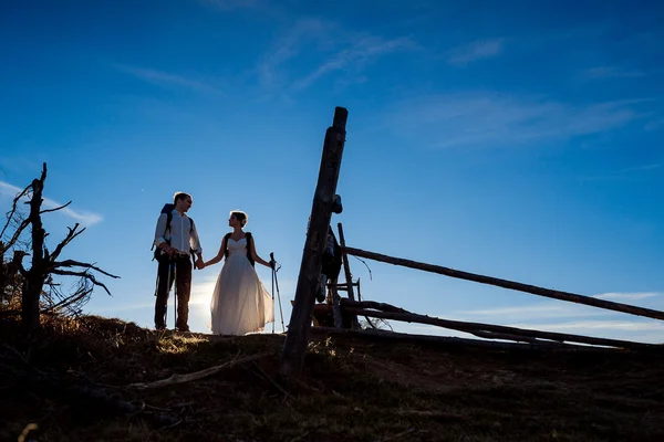 Happy newlyweds walking with mountain equipment on the Alpine countryside — Stock fotografie