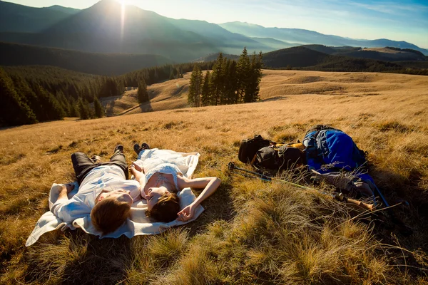 Romantische bruidspaar liggend op het gras in Bergen. — Stockfoto