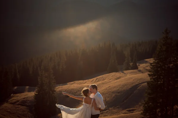 Adorável casal de casamentos a beijar. Bela paisagem de montanha no fundo — Fotografia de Stock