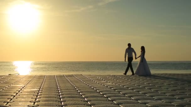 在日落走在海滩上的浪漫婚礼夫妇的身影。埃及度蜜月 — 图库视频影像
