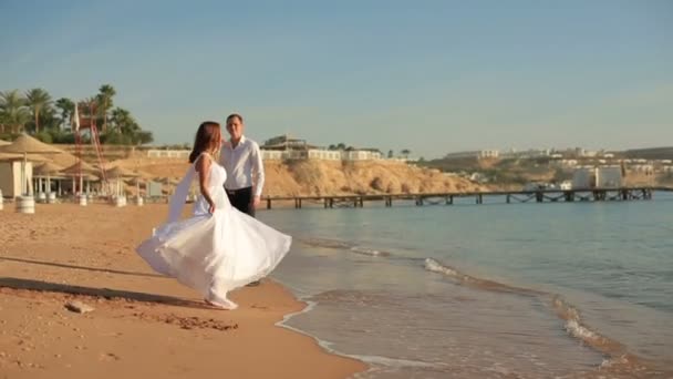 Lyckliga bruden och brudgummen att ha kul på stranden. Smekmånad — Stockvideo