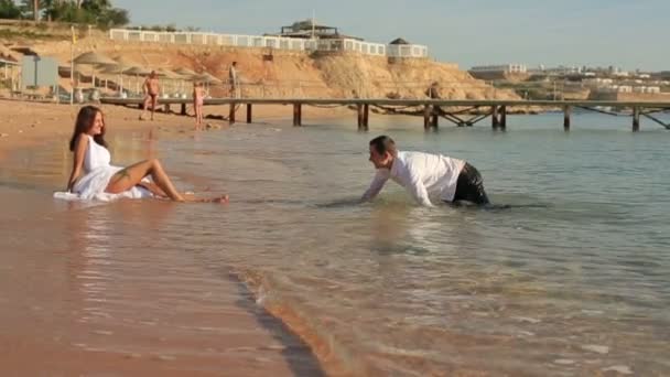 Novio juguetonamente arrastrándose a cuatro patas con su novia. Playa soleada en Egipto — Vídeo de stock