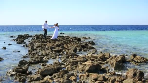 Hermosa pareja de boda posando en la orilla apedreada. Luna de miel en Egipto — Vídeos de Stock