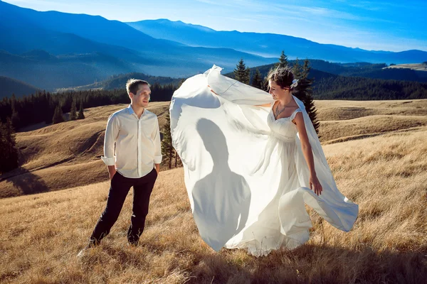 Прекрасная невеста изящно танцует перед женихом на поле. Медовый месяц в Альпах — стоковое фото