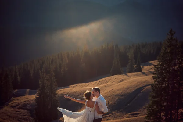 Adorável casal de casamentos a beijar. Bela paisagem de montanha no fundo — Fotografia de Stock