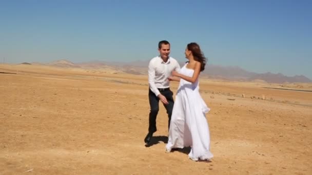 Groom holds in hands his beautiful bride. Sunny beach background. Honeymoon — Stock Video