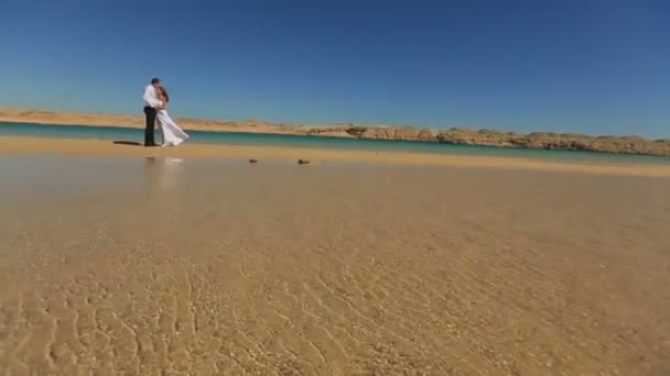 Lyckliga bruden och brudgummen kramar mjukt på stranden i Egypten. Exotiska smekmånad — Stockvideo