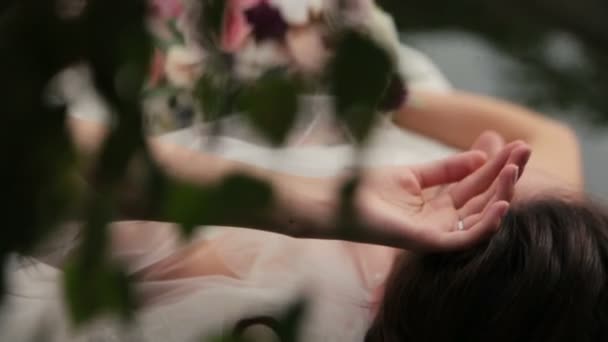 Superbe mariée brune allongée sur le bateau avec bouquet dans les mains 