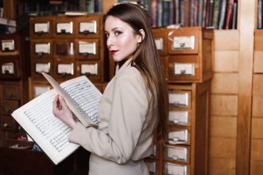 Şık genç iş kadını bardaklarda bir kütüphanede okuma kitap