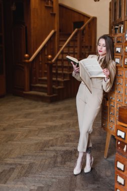 Güzel genç şık kız kütüphanede kitap okuma