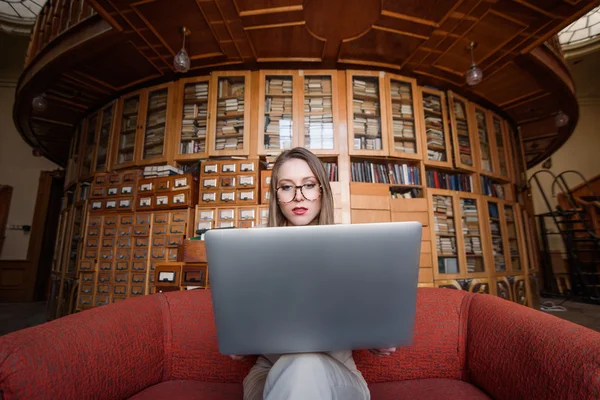 Femme d'affaires assis sur le canapé rouge et travaille dans son ordinateur portable — Photo