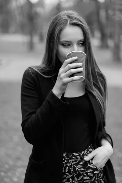 Портрет молодой красивой девушки, пьющей кофе в парке. Черно-белое фото — стоковое фото