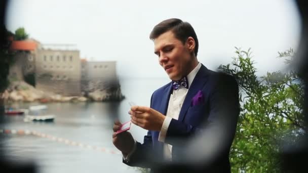 Lo sposo eccitato si pulisce la fronte con una splendida vista sul Montenegro, Budva sullo sfondo — Video Stock