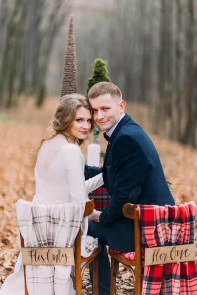 Svatební pár pózuje a drželi se za ruce v tabulce volna v podzimním lese — Stock fotografie