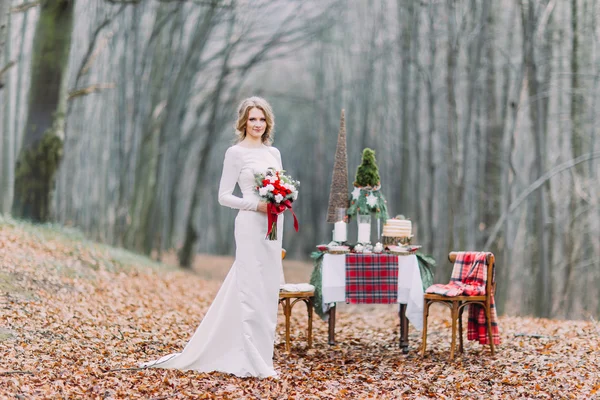 Schöne blonde Braut in der Nähe von Weihnachtstisch im Wald — Stockfoto