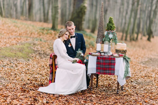 Charmant couple de mariage assis et câlin à la table de vacances dans la forêt d'automne — Photo