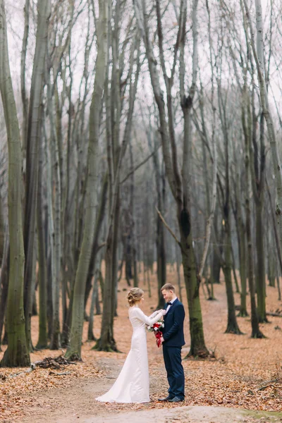 Mariée ajuste boutonnière sur le costume de son marié dans la forêt d'automne — Photo