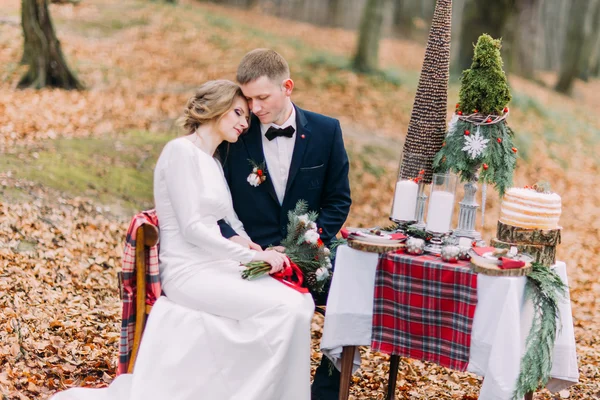 Casal de casamento encantador sentado e abraçando na mesa de férias na floresta de outono — Fotografia de Stock