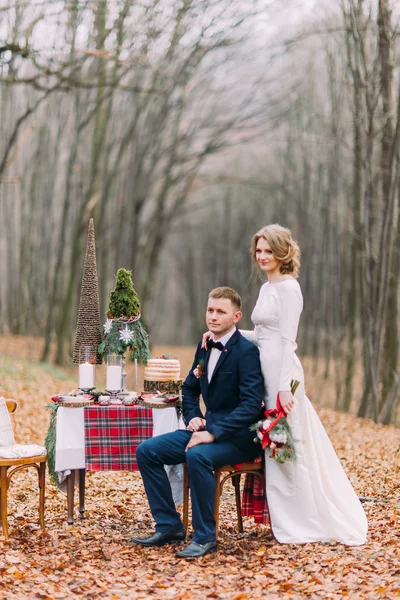 Casal bonito posando perto da mesa decorada para férias de Natal na floresta de outono . — Fotografia de Stock