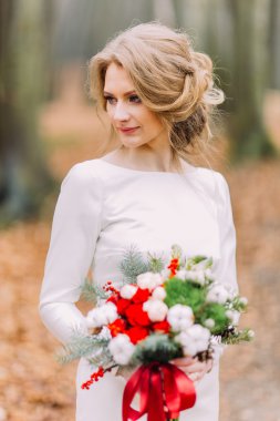 Güzel sarışın gelin ile sonbahar parkta kırmızı ve beyaz gül buketi