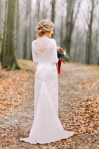 Hermosa novia rubia en vestido de novia de encaje largo en la vista posterior del bosque de otoño — Foto de Stock