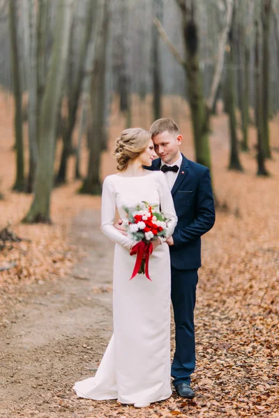 Bello sposo e bella sposa si guardano amorevolmente nella foresta autunnale — Foto Stock