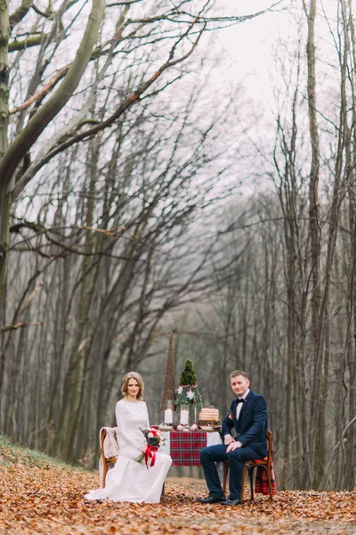 Casamento casal sentado na mesa de férias na floresta de outono — Fotografia de Stock