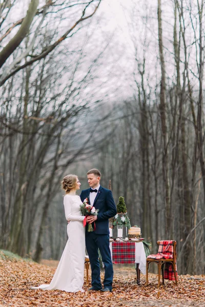 Весільний пара поблизу на оформлені для різдвяних свят таблиці в осінньому лісі. — стокове фото
