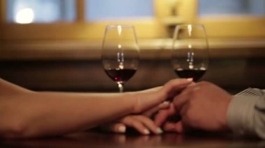 Elele ve romantik akşam yemeği sırasında kırmızı şarap bardakları tokuşturup sevgi dolu çiftin yakın çekim.