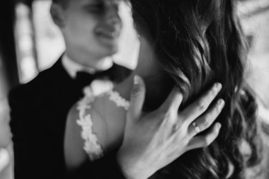 Black and white close up portrait of handsome young groom embracing his wife
