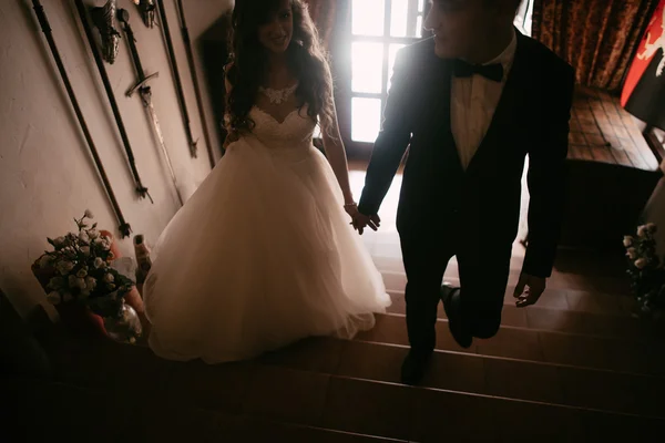 Feliz casal recém-casado escalando as escadas e de mãos dadas — Fotografia de Stock