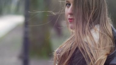 Kırmızı dudaklı, zarif hippi kız güzel yüzüne hafifçe dokunuyor. Autumn Park geçmişi. Yavaş çekim videosu