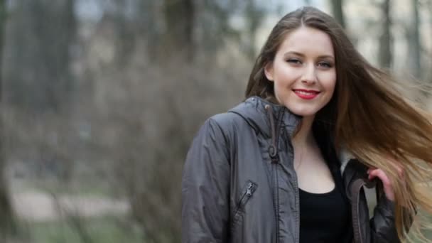 Giovane ragazza hipster elegante con labbra rosse sorridenti e in posa per la fotocamera nel parco autunnale. Video al rallentatore — Video Stock
