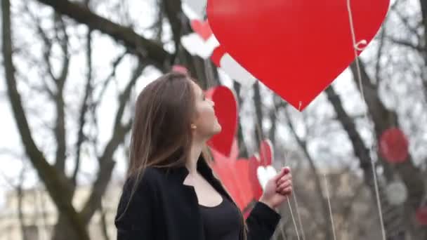 Hermosa chica de moda urbana joven juega con la decoración de corazones de papel en el parque de otoño. Concepto de San Valentín . — Vídeos de Stock