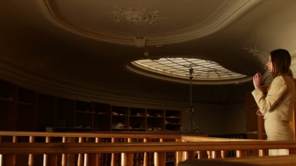 Jeune femme d'affaires attrayant enlève des lunettes et marche prudemment d'avant en arrière. Ancienne bibliothèque vintage sur fond . — Video