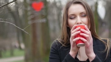 Sonbahar parkı arka planda poz ve paket kahve fincan içme genç güzel sarışın hipster kadın Portresi