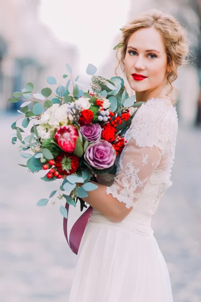 Привлекательная блондинка невеста с огромным букетом роз и пионов смотрит в камеру — стоковое фото
