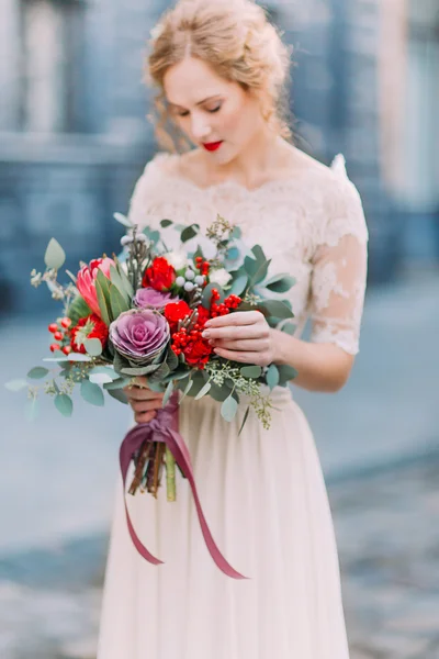 Belle mariée avec les yeux fermés tient un énorme bouquet de roses et de pivoines avec une architecture européenne ancienne sur fond — Photo